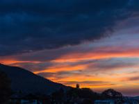 Glühen zwischen Bergkamm und dunkler Wolkenwand